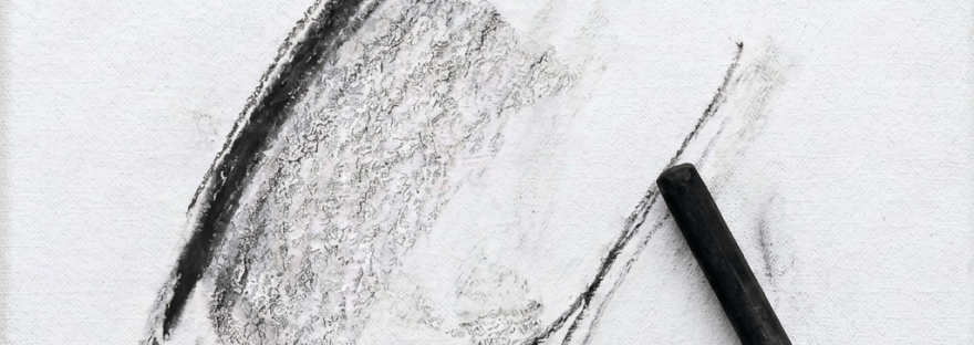 Hand using charcoal to sketch a portrait on an easel-mounted canvas
