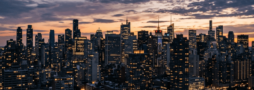 Illuminated city skyline and waterfront beneath dramatic evening clouds